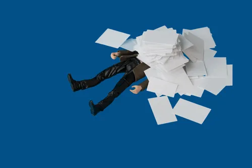 An illustrated figure buried under a pile of paperwork